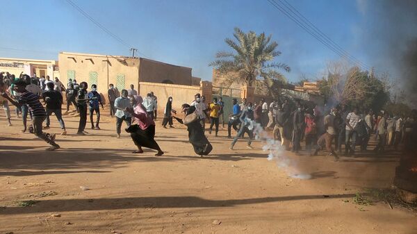 متظاهرون سودانيون يركضون من عبوة غاز مسيل للدموع أطلقها رجال شرطة مكافحة الشغب لتفريقهم وهم يشاركون في مظاهرات مناهضة للحكومة في أم درمان بالخرطوم - سبوتنيك عربي