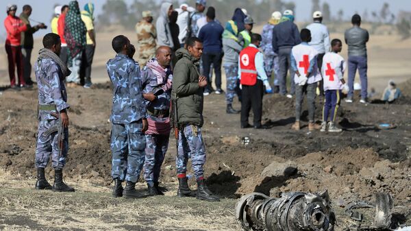 رجال من الشرطة الفيدرالية الإثيوبية يقفون بالقرب من أجزاء المحرك في مكان تحطم طائرة الخطوط الجوية الإثيوبية بالقرب من مدينة بيشوفو - سبوتنيك عربي