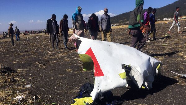 أشخاص يمشون بجوار جزء من الحطام في مكان تحطم طائرة الخطوط الجوية الإثيوبية بالقرب من مدينة بيشوفو جنوب شرق أديس أبابا - سبوتنيك عربي