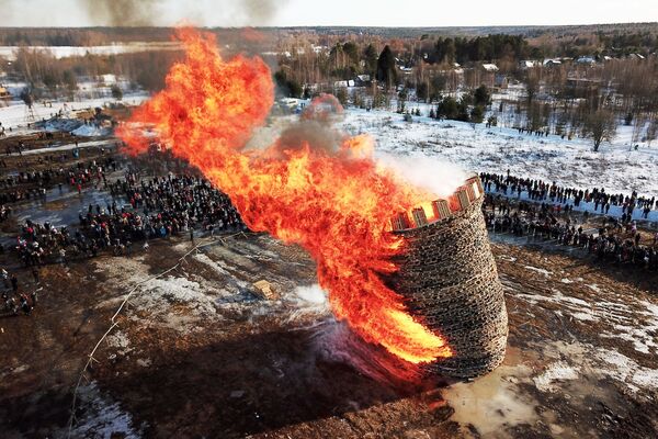 المشاركون في الاحتفال بمهرجان ماسلينيتسا (أسبوع المرافع)  أثناء حرق نموذج من القش في أراضي قرية نيكولا لينيفيتس الروسية - سبوتنيك عربي