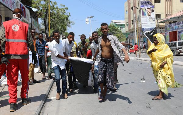 مدنيون يحملون جثة رجل قتل في انفجار سيارة مفخخة بالقرب من فندق في مقديشو - سبوتنيك عربي