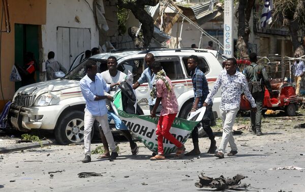 مدنيون يحملون جثة رجل قتل في انفجار سيارة مفخخة بالقرب من فندق في مقديشو - سبوتنيك عربي