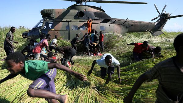 سكان محليون يركضون باتجاه طائرة هليكوبتر تابعة لجيش الدفاع الوطني لجنوب إفريقيا، التي نقلت المساعدات الغذائية إلى القرية المتضررة من الإعصار أيداي، موزمبيق 26 مارس/ آذار 2019 - سبوتنيك عربي