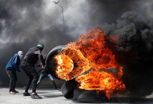متظاهرون فلسطينيون وإطارات مشتعلة خلال اشتباكات مع القوات الإسرائيلية بالقرب من مستوطنة بيت إيل في الضفة الغربية، 27 مارس/ آذار 2019 - سبوتنيك عربي