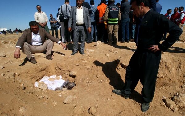 رجال أكراد ينظرون إلى العظام المغطاة من مقبرة جماعية اكتشفت للأكراد في غرب مدينة السماوة - سبوتنيك عربي