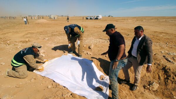 أعضاء من الدفاع المدني العراقي يغطون عظام مقبرة جماعية مكتشفة للأكراد غرب مدينة السماوة - سبوتنيك عربي