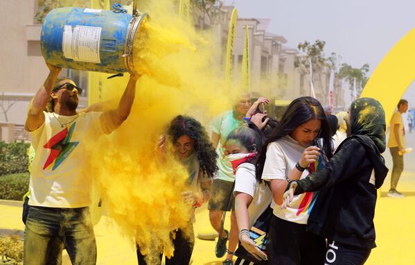 متطوعون يصبون مسحوقا من اللون الأصفر على المتسابقين الذين اجتازوا خط نهاية السباق، في أول مسابقة الألوان في الجيزة، مصر في 13 أبريل/ نيسان 2019 - سبوتنيك عربي