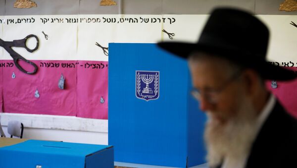 رجل يهودي متشدد يمشي بجانب كشك الاقتراع وصندوق الاقتراع في مركز اقتراع بينما يصوت الإسرائيليون في الانتخابات البرلمانية في القدس - سبوتنيك عربي