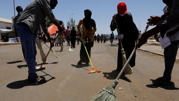 متظاهرون سودانيون يكنسون الطريق أثناء احتجاج أمام وزارة الدفاع في الخرطوم - سبوتنيك عربي