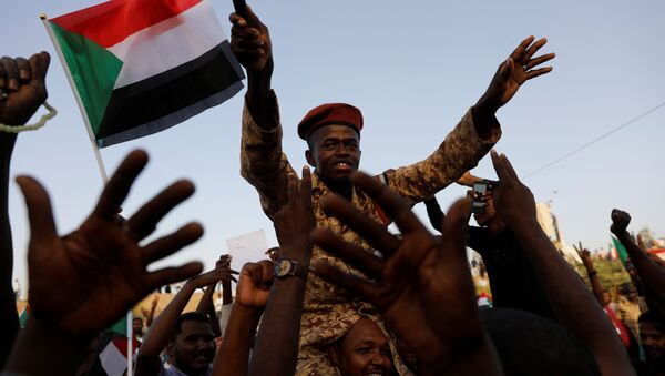 جندي سوداني يجلس على أكتاف أحد المتظاهرين وهو يهتف مع الحشد خارج وزارة الدفاع في الخرطوم - سبوتنيك عربي