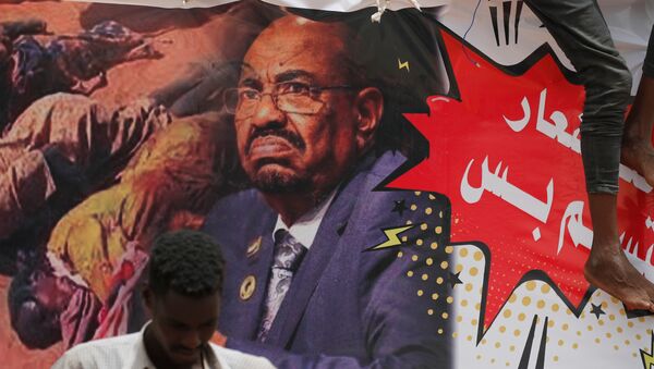 متظاهرون في السودان يرفعون لافتات عليها صورة الرئيس المعزور عمر البشير - سبوتنيك عربي