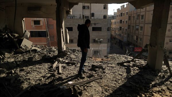 فلسطيني يتفقد مبنى دمرته الضربات الجوية الإسرائيلية في مدينة غزة - سبوتنيك عربي