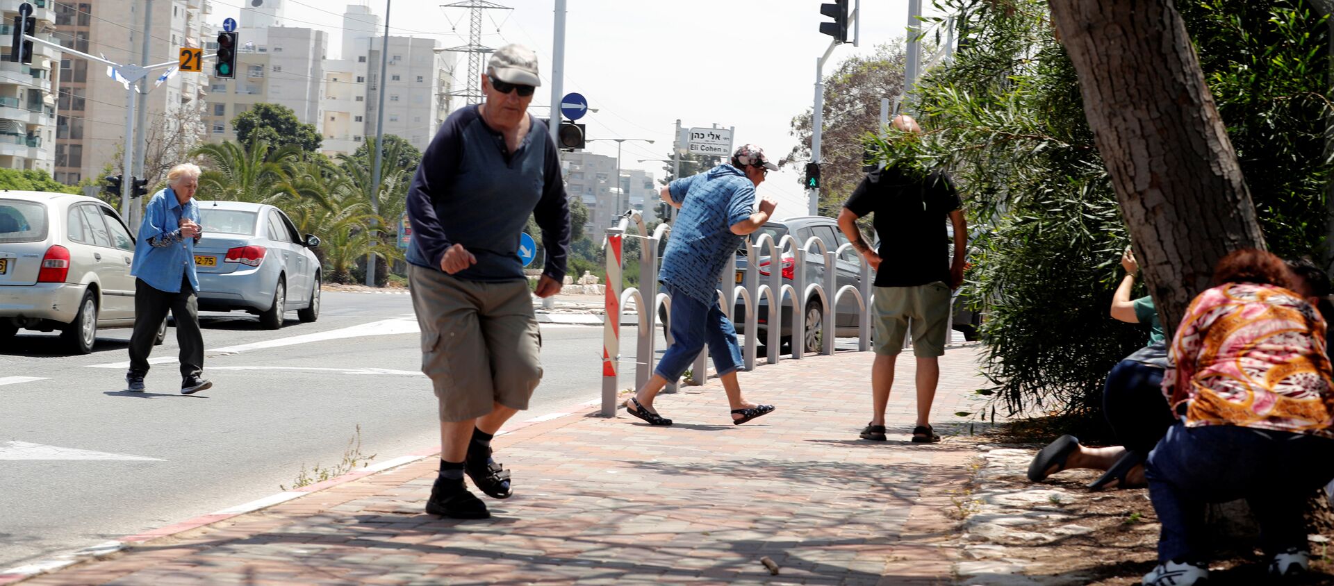 إسرائيليون يركضون للاحتماء وهم يسمعون صفارات الإنذار تحذر من الصواريخ القادمة من غزة في مدينة عسقلان جنوبي إسرائيل - سبوتنيك عربي, 1920, 22.10.2021
