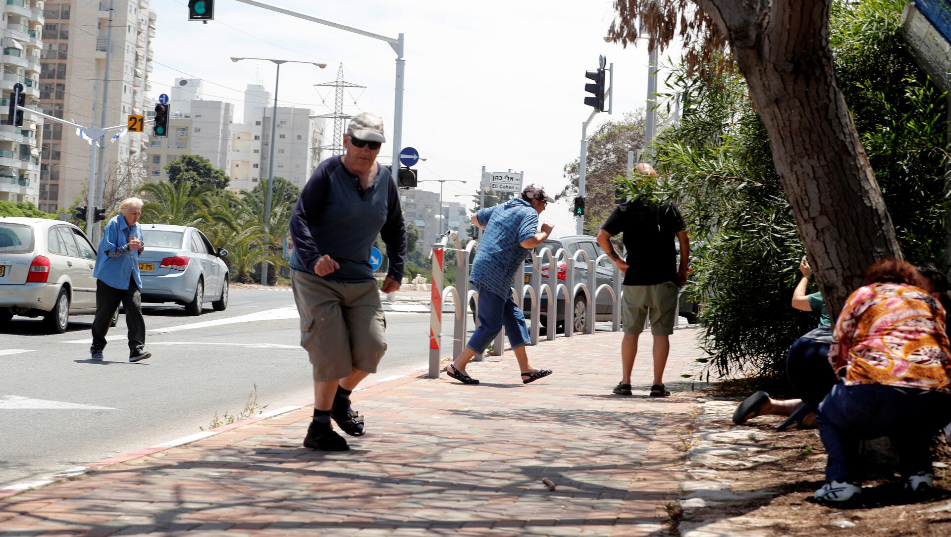 إسرائيليون يركضون للاحتماء وهم يسمعون صفارات الإنذار تحذر من الصواريخ القادمة من غزة في مدينة عسقلان جنوبي إسرائيل - سبوتنيك عربي, 1920, 22.10.2021