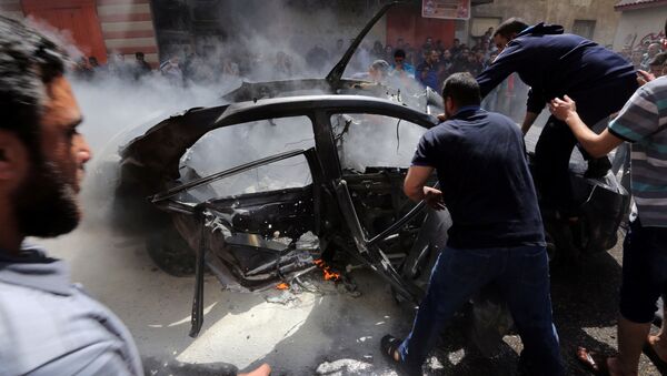 يحاول الفلسطينيون إطفاء حريق في سيارة أحد قادة حماس حامد أحمد عبد الخضري الذي قتل في غارة جوية إسرائيلية في مدينة غزة - سبوتنيك عربي