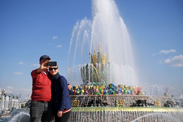 سياح يلتقطون صورة على خلفية نافورة كاميني تسيفتوك في حديقة في دي إن خا في موسكو - سبوتنيك عربي