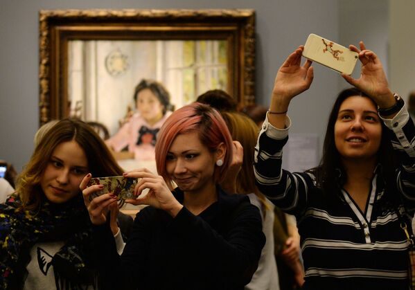 زوار متحف تريتياكوفسكايا غاليريا يلتقطون صور سيلفي على خلفية لوحة الفتاة والخوخ الشهيرة للرسام الروسي فالنتين سيروف، في موسكو - سبوتنيك عربي