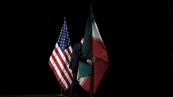 موظف يرفع العلم الإيراني من المسرح بعد صورة جماعية مع وزراء الخارجية وممثليهم خلال المحادثات النووية الإيرانية في مركز فيينا الدولي في فيينا - سبوتنيك عربي