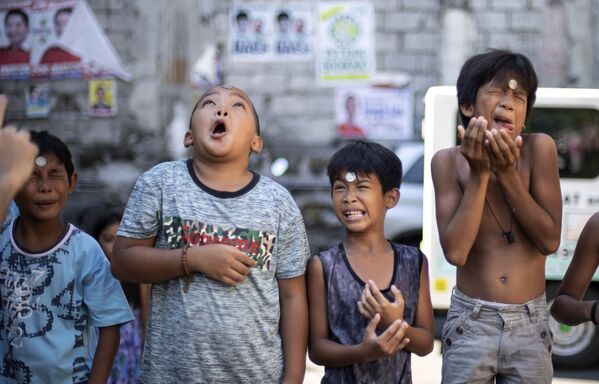 أولاد خلال مسابقة تحريك عملة معدنية من جبهة الرأس وصولا إلى الفم، في المهرجان السنوي على شرف القديسة ريتا كاشييسكايا في مانيلا، 19 مايو/ أيار 2019 - سبوتنيك عربي