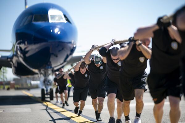 المشاركون في المسابقة السنوية Plane Pull لسحب طائرة من طراز جيت بليو أ320 (JetBlue A320) في مطار جون كينيدي الدولي في نيويورك، 21 مايو/ أيار 2019 - سبوتنيك عربي