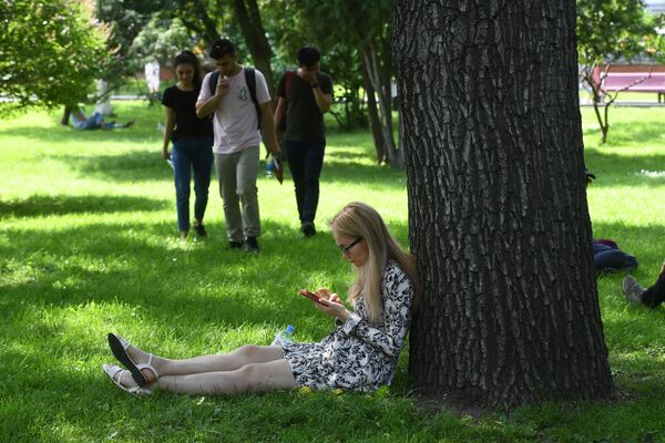 فتاة تستظل بجشرة في حديقة ألكسندروفسكي ساد بالقرب من الساحة الحمراء - سبوتنيك عربي