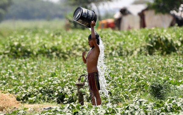 صبي هندي يصب الماء على نفسه أثناء محاولته لتبريد نفسه وسط ارتفاع درجات الحرارة في نيودلهي في 29 مايو/ أيار 2019 - سبوتنيك عربي