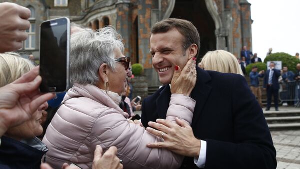 الرئيس الفرنسي إيمانويل ماكرون يبتسم لأحد مؤيديه بعد التصويت في الانتخابات البرلمانية الأوروبية في لو توكيه، شمال فرنسا، الأحد 26 مايو/ أيار 2019 - سبوتنيك عربي