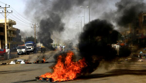 متظاهرون سودانيون يستخدمون الإطارات المحترقة لإقامة حاجز في أحد الشوارع - سبوتنيك عربي