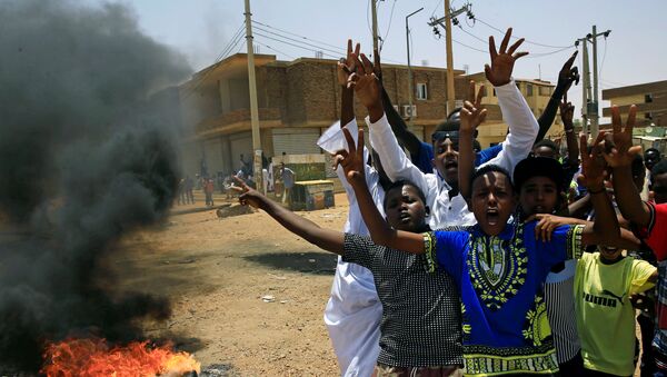 متظاهرون سودانيون يهتفون بشعارات عند أحد المتاريس مطالبين المجلس العسكري الانتقالي في البلاد بتسليم السلطة إلى المدنيين - سبوتنيك عربي