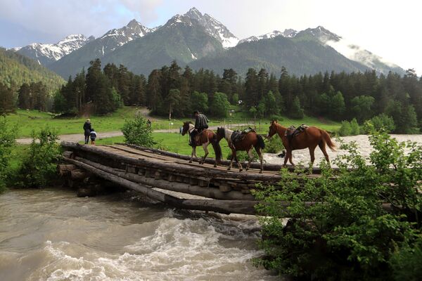 أحد راكبي الخيول يعبر جسرا خشبيا فوق نهر جبلي في أراضي وادي صوفيا في جمهورية كراتشاي - تشركيسيا - سبوتنيك عربي