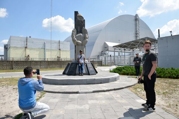 سياح يلتقطون صورة تذكارية على خلفية نصب تذكاري الذي شيد لمكافحي كارثة تشيرنوبل - سبوتنيك عربي
