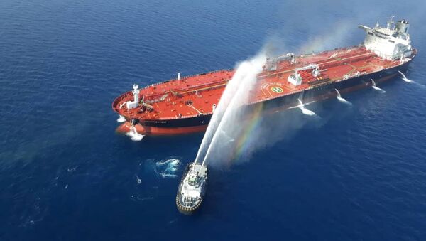 قارب من البحرية الإيرانية يحاول إطفاء نيران ناقلة النفط بعد أن تعرضت للهجوم في خليج عمان - سبوتنيك عربي