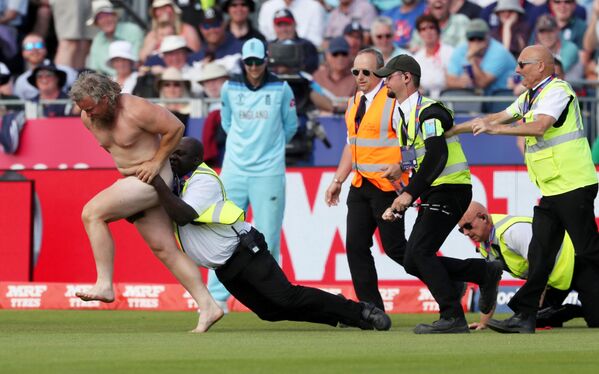 عناصر الأمن يحاولون القبض على رجل عاري خرج إلى أرض الملعب خلال مباراة كريكيت بين فريقي إنجلترا ونيوزيلندا، بريطانيا 3 يوليو/ تموز 2019 - سبوتنيك عربي