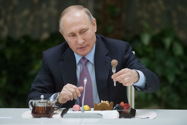 الرئيس فلاديمير بوتين يتناول الحلويات أثناء اجتماعه مع الفائزين في مسابقة عائلة العام في روسيا - سبوتنيك عربي