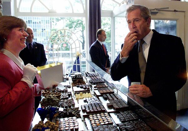 الرئيس الأمريكي السابق جورش بوش الابن يتذوق حلوى الشوكولاتة في أحد متاجر الشوكولاتة في بروكسل، بلجيكا 13 يونيو/ حزيران 2001 - سبوتنيك عربي