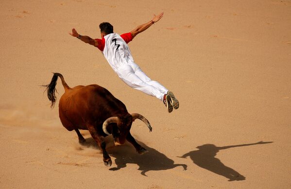 أحد الـريكورتادور يقفز فوق الثور خلال مسابقة مصارعة الثيران في مهرجان سان فيرمين في بامبلونا، إسبانيا 13 يوليو/ تموز 2019 - سبوتنيك عربي