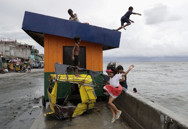 أطفال يقفزون إلى المياه في خليج مانيلا بالفلبين بعد هطول أمطار غزيرة - سبوتنيك عربي