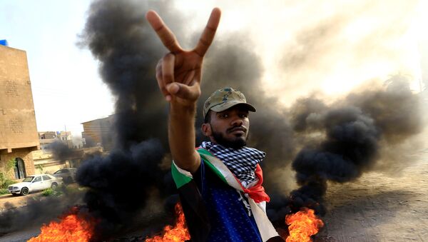 متظاهر يحرق الإطارات أثناء مظاهرة مناهضة لتقرير النائب العام عن فض الاعتصام في الخرطوم - سبوتنيك عربي