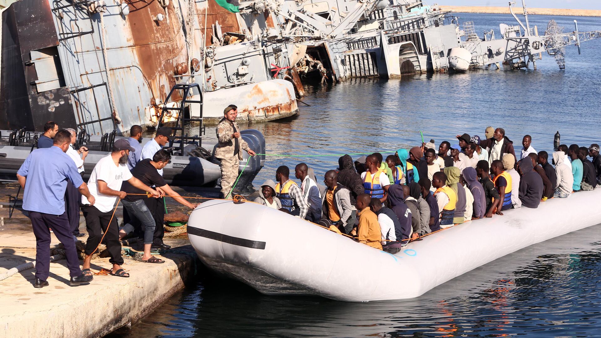  خفر السواحل الليبي يقوم بسحب قارب يحمل مهاجرين أفارقة، تم إنقاذهم أثناء محاولتهم الوصول إلى أوروبا بطريقة غير شرعية، في قاعدة بحرية بالقرب من العاصمة طرابلس في 29 سبتمبر/ أيلول 2015. - سبوتنيك عربي, 1920, 25.11.2021