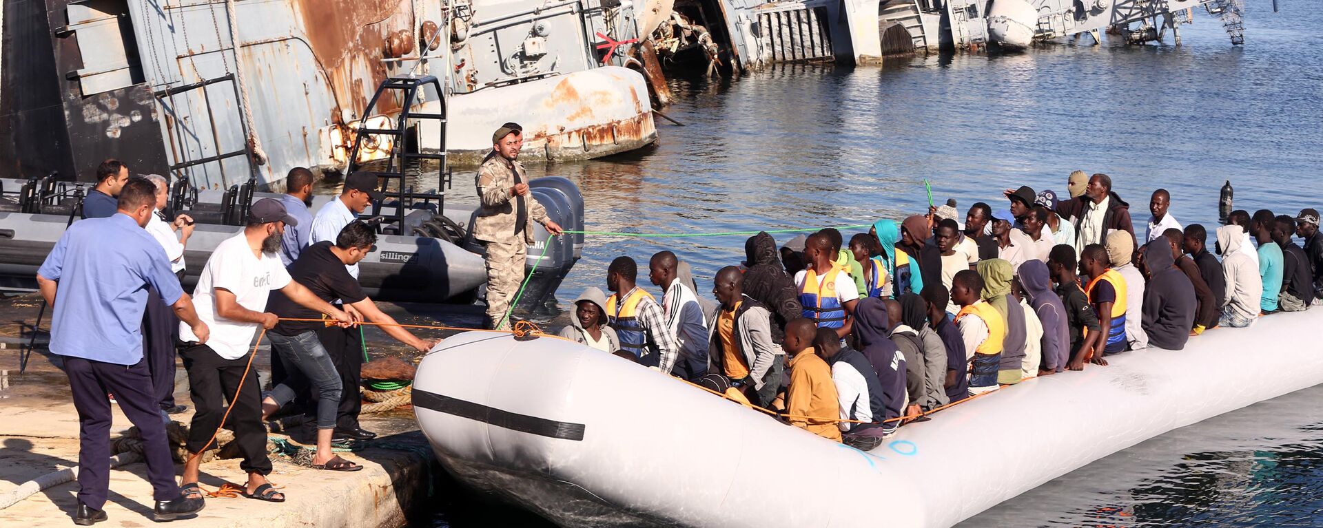  خفر السواحل الليبي يقوم بسحب قارب يحمل مهاجرين أفارقة، تم إنقاذهم أثناء محاولتهم الوصول إلى أوروبا بطريقة غير شرعية، في قاعدة بحرية بالقرب من العاصمة طرابلس في 29 سبتمبر/ أيلول 2015. - سبوتنيك عربي, 1920, 12.10.2021