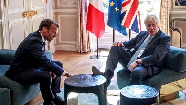 رئيس وزراء بريطانيا بوريس جونسون يضع قدمه على طاولة أمام الرئيس الفرنسي إيمانويل ماكرون بداخل قصر الإليزيه بالعاصمة الفرنسية باريس، 22 أغسطس/آب 2019 - سبوتنيك عربي