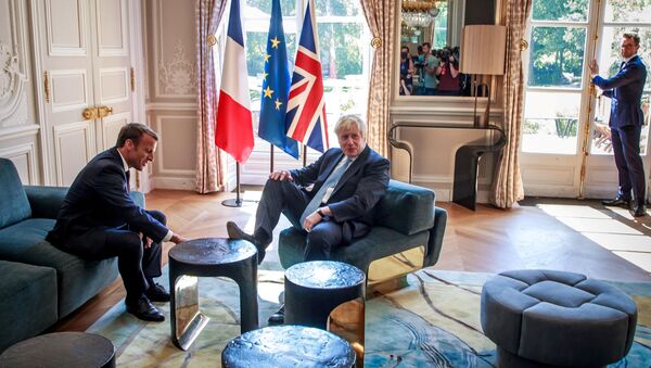 رئيس وزراء بريطانيا بوريس جونسون يضع قدمه على طاولة أمام الرئيس الفرنسي إيمانويل ماكرون بداخل قصر الإليزيه بالعاصمة الفرنسية باريس، 22 أغسطس/آب 2019 - سبوتنيك عربي
