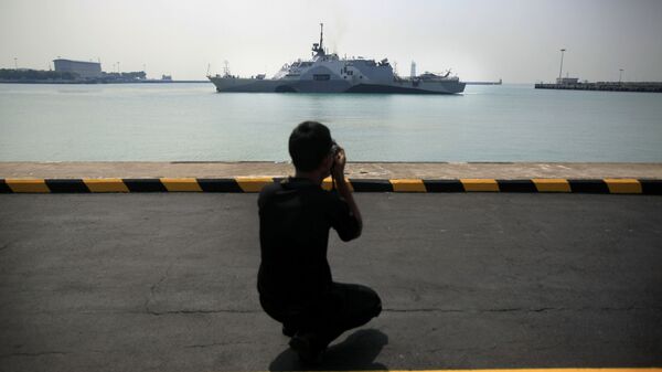 رجل يصور سفينة تابعة للبحرية الأمريكية يو إس إس فريدوم (LCS 1) أثناء رسوها رصيفها في قاعدة شانغي البحرية في سنغافورة - سبوتنيك عربي