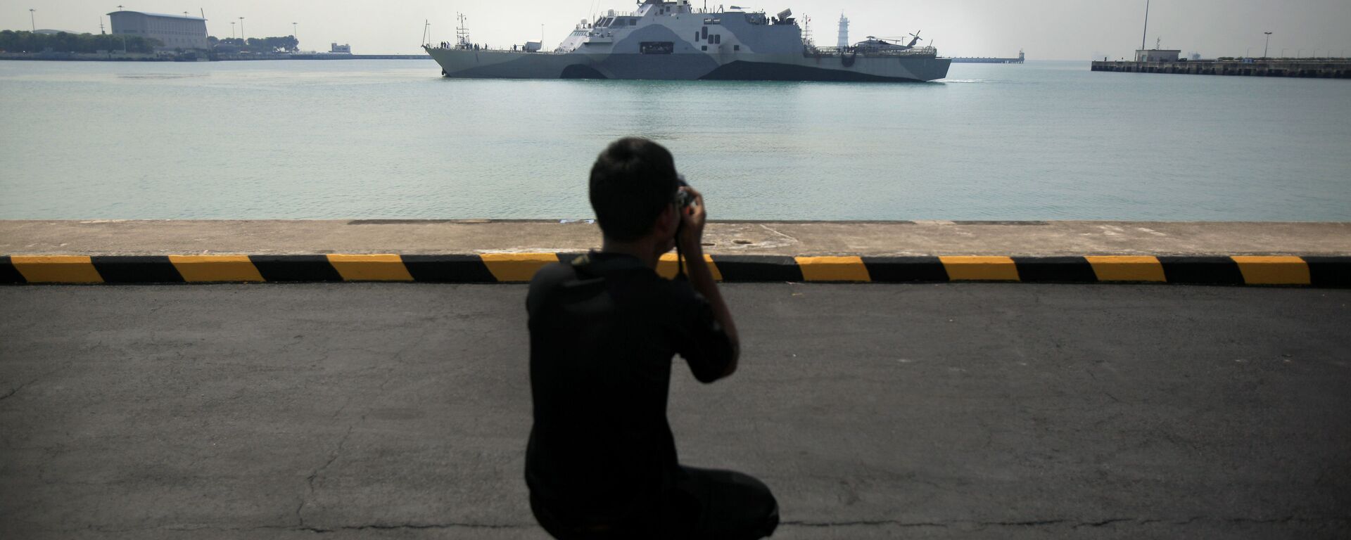 رجل يصور سفينة تابعة للبحرية الأمريكية يو إس إس فريدوم (LCS 1) أثناء رسوها رصيفها في قاعدة شانغي البحرية في سنغافورة - سبوتنيك عربي, 1920, 25.12.2021