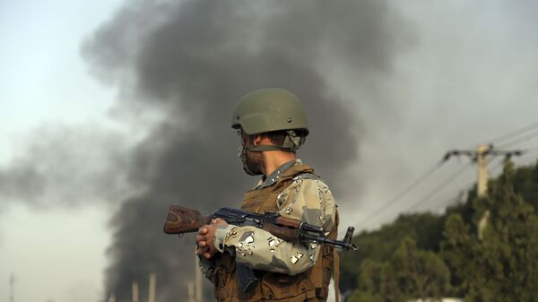 صورة أرشيفية لجندي أفغاني، ودخان متصاعد جراء حادث إرهابي. - سبوتنيك عربي