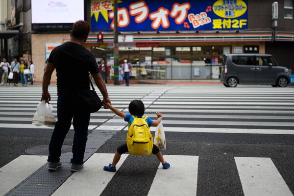 رجل وابنه ينتظران إشارة المرور لعبور الشارع في مدينة أويتي، اليابان 21 سبتمبر 2019 - سبوتنيك عربي