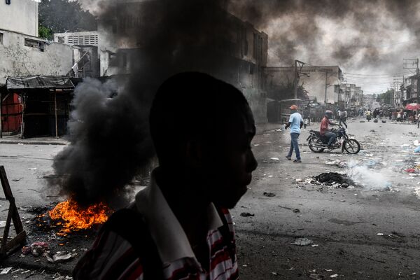 رجل يسير بجوار إطارات محترقة أثناء احتجاجات في بورت أو برنس، هايتي 25 سبتمبر 2019 - سبوتنيك عربي