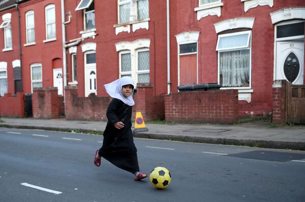 طفلة تلعب بالكرة في إحدى شوارع مدينة لندن البريطانية - سبوتنيك عربي