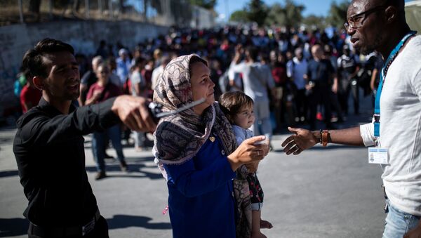 مهاجرة من مخيم موريا وطفلها يستعدان لصعود حافلة إلى ميناء ميتيليني حيث سيتم نقلهما إلى البر الرئيسي في جزيرة ليسبوس في اليونان - سبوتنيك عربي