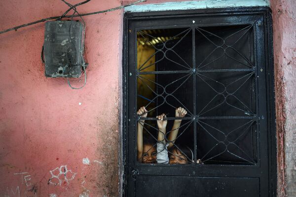 أطفال يلعبون خلف الباب، في بيتاري الفقيرة في كاراكاس، فنزويلا، 29 سبتمبر 2019 - سبوتنيك عربي